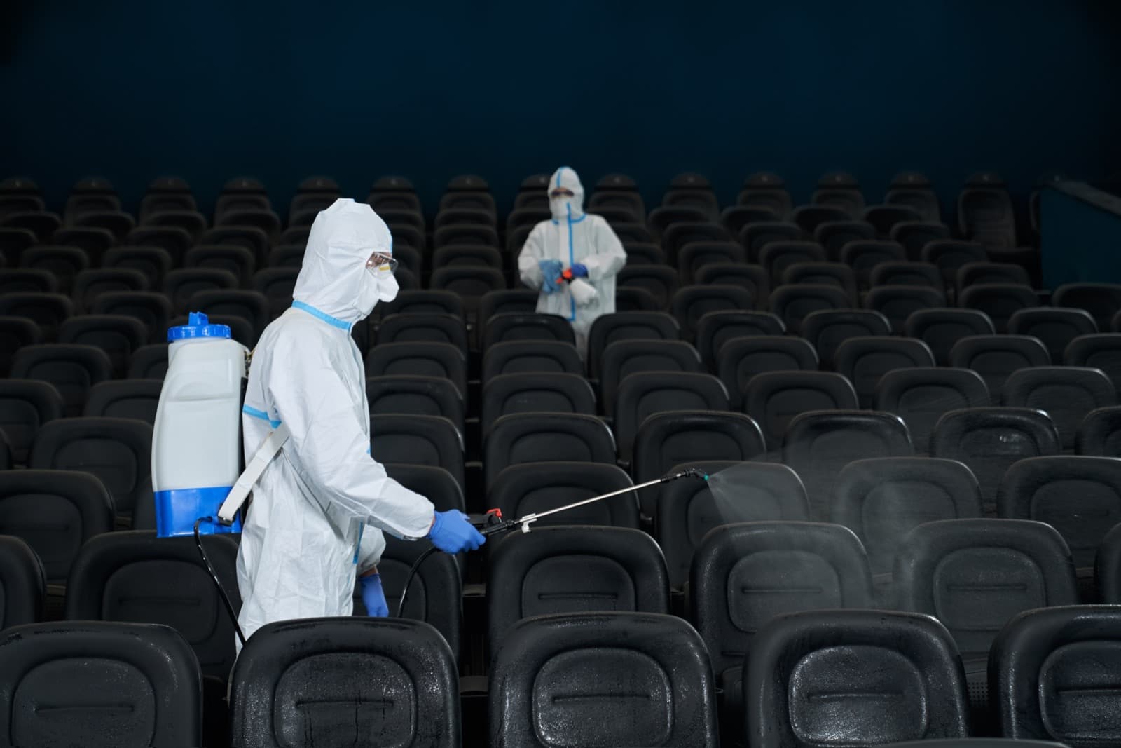 Dos operarios con traje de protección desinfectando una sala